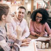 Two woman and man sitting at a table and talking. 