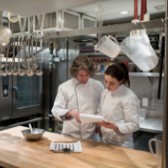 Two chefs looking at recipe in a commercial kitchen. 