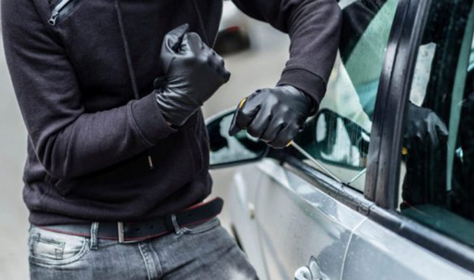 Man in mask breaking into car.