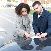 Man and woman filling out paper after car accident. 