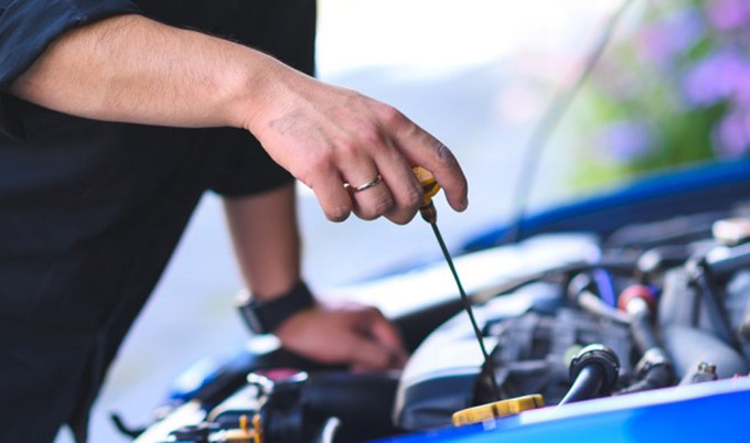 Man checking a car's engine oil level. 