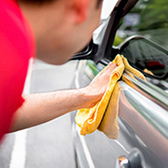 Man wiping car with microfiber cloth. 