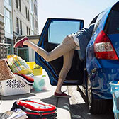 Young woman unpacking car outside of dorm. 