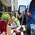 Young woman unpacking car outside of dorm. 