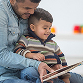 Dad reading board book with son. 