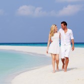 Man and woman walking barefoot on the beach. 