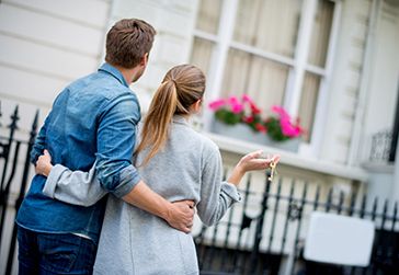 Couple hugging and holding house keys.