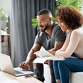 Couple sitting looking at laptop. 