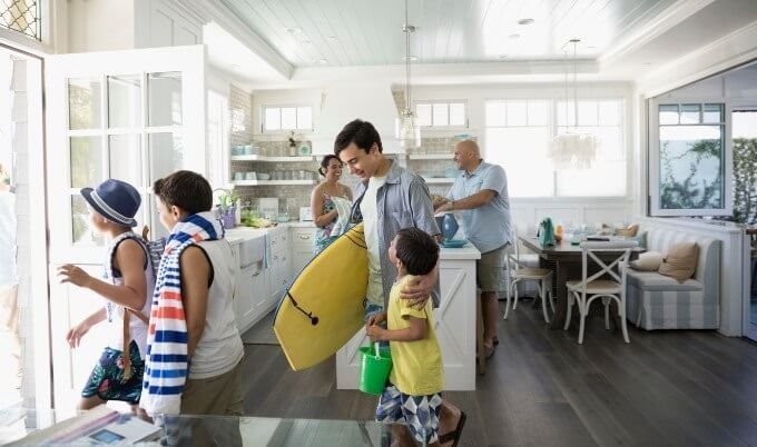 Family members leaving vacation home with towels and beach toys.
