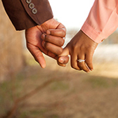 Woman wearing engagement ring holding hands with partner. 