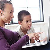 Woman and boy using computer. 