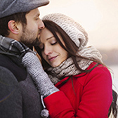 Woman and man wearing coats and hugging.