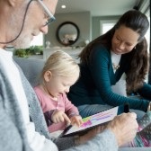 Grandparents sitting with granddaughter and drawing on a tablet. 