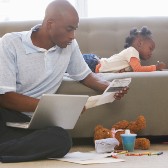 Man looking at paperwork while little girl colors. 