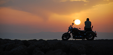 Person sitting on a motorcycle at sunset. 