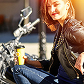 Woman drinking coffee on motorcycle. 