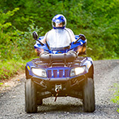 Man of blue ATV on a dirt road.