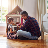 Dad and daughter playing with dollhouse. 