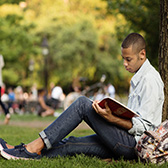 Student reading under a tree.