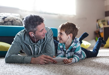 Dad and son sharing headphones and listening to music. 