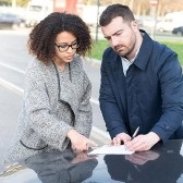 A man and woman exchange information after a vehicle accident.