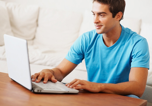 A young man looking for car insurance on his laptop. He is reading an article to understand some common concepts.