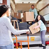 Parents and daughter taking boxes off moving truck.
