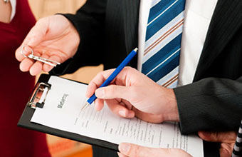 A new tenant is signing the lease while the landlord is prepare to hand him keys.