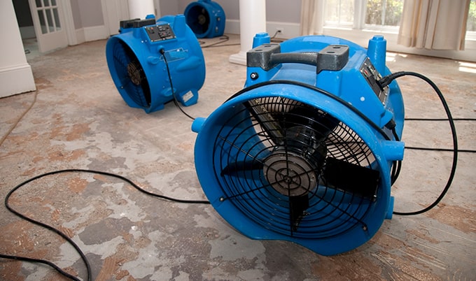Industrial fans drying out a flooded home.